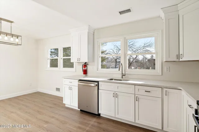 a kitchen with white cabinets and wooden floor