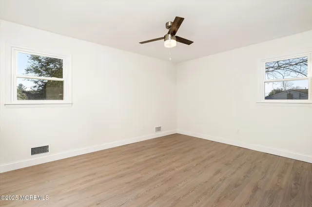 a view of a big room with wooden floor and windows