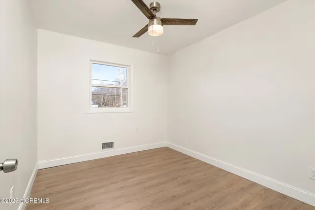 an empty room with wooden floor and ceiling fan