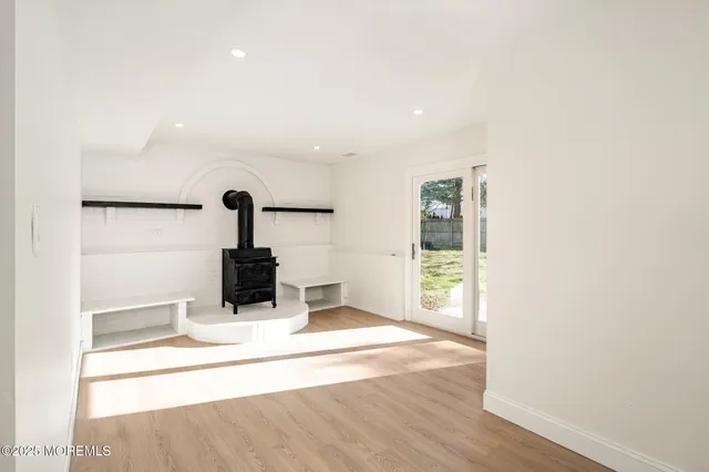 an empty room with wooden floor and way to kitchen