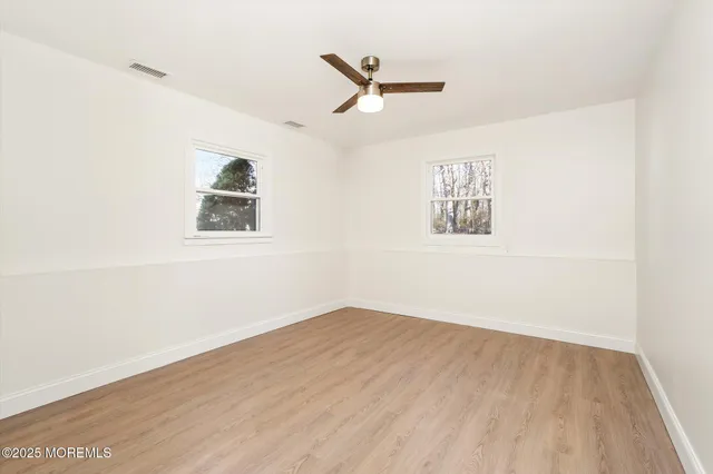 an empty room with a window and ceiling fan