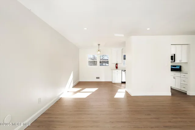 a view of a kitchen with wooden floor and white kitchen