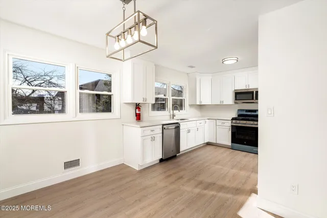 a kitchen with granite countertop white cabinets and stainless steel appliances