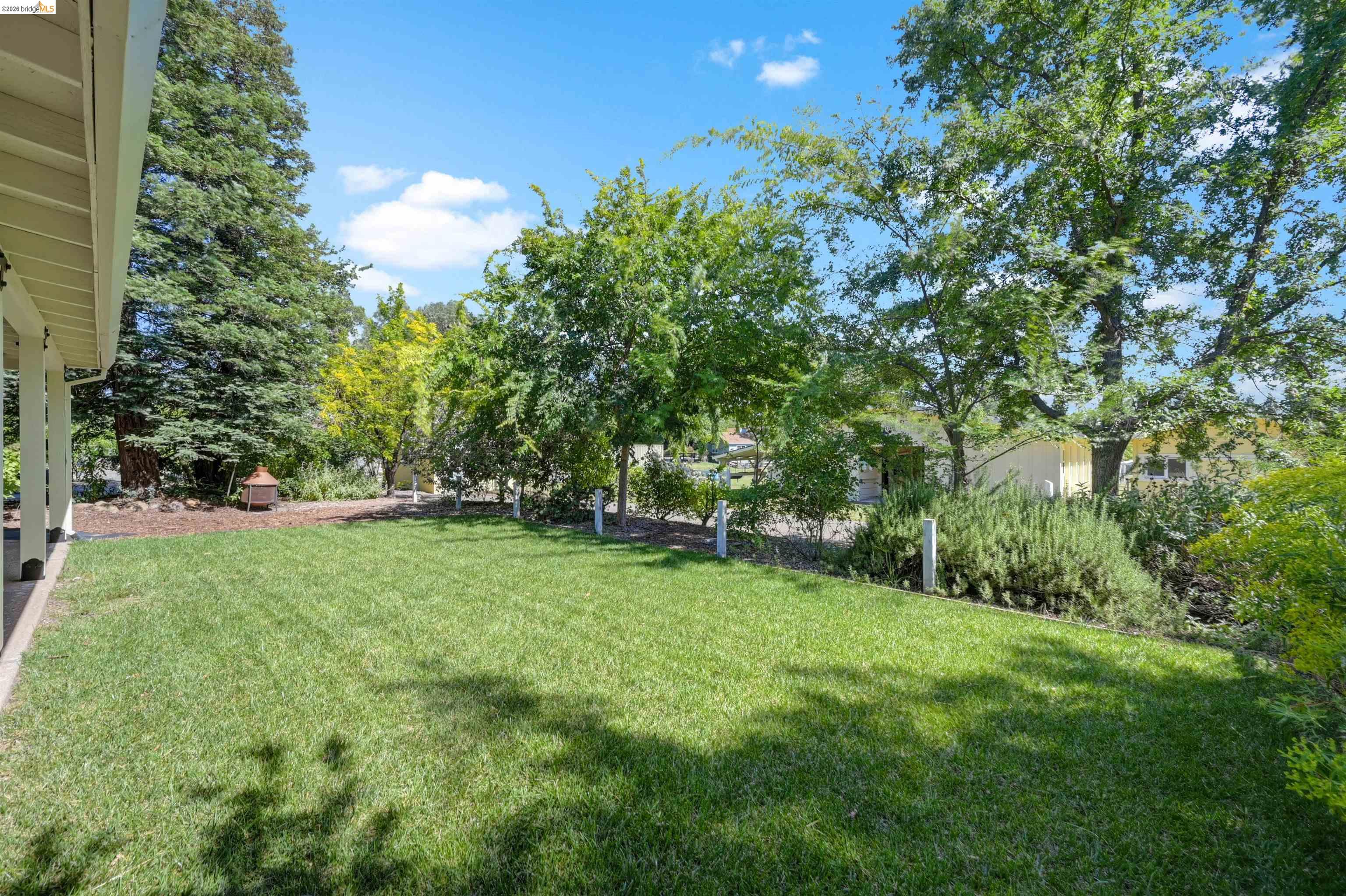 10474 Sheldon Road Elk Grove, CA 95624 - Photo 48 of 83 Spacious lawn area framed by mature trees, a covered patio, and landscaped beds