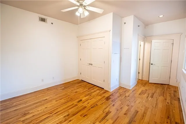 an empty room with wooden floor closet and windows