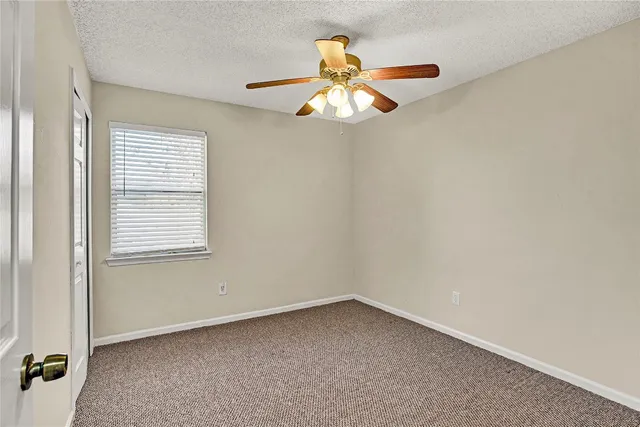 an empty room with a window and a fan
