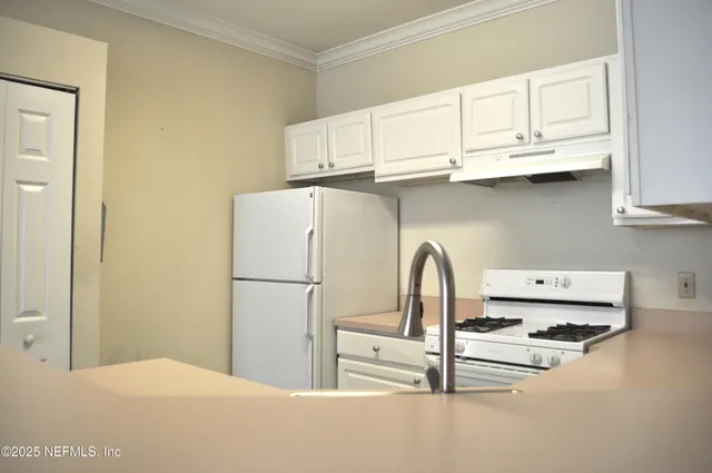 a close view of a refrigerator a sink and dishwasher with white cabinets