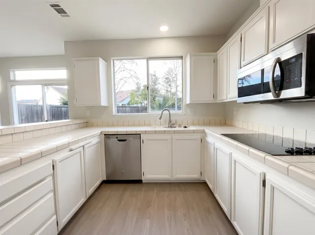 a kitchen with a sink white cabinets and white appliances