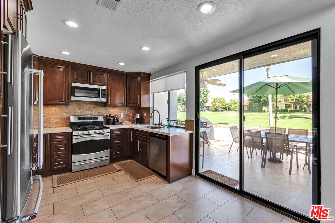 109 Torremolinos Drive Rancho Mirage, CA 92270 - Photo 28 of 39 a kitchen with stainless steel appliances granite countertop a stove top oven a sink and a refrigerator
