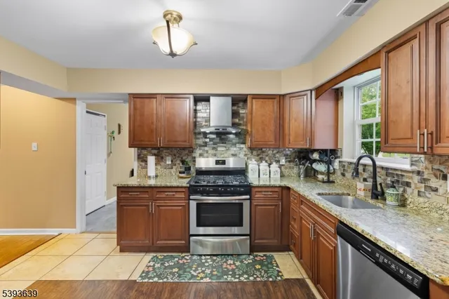 a kitchen with stainless steel appliances granite countertop a stove a sink and a refrigerator