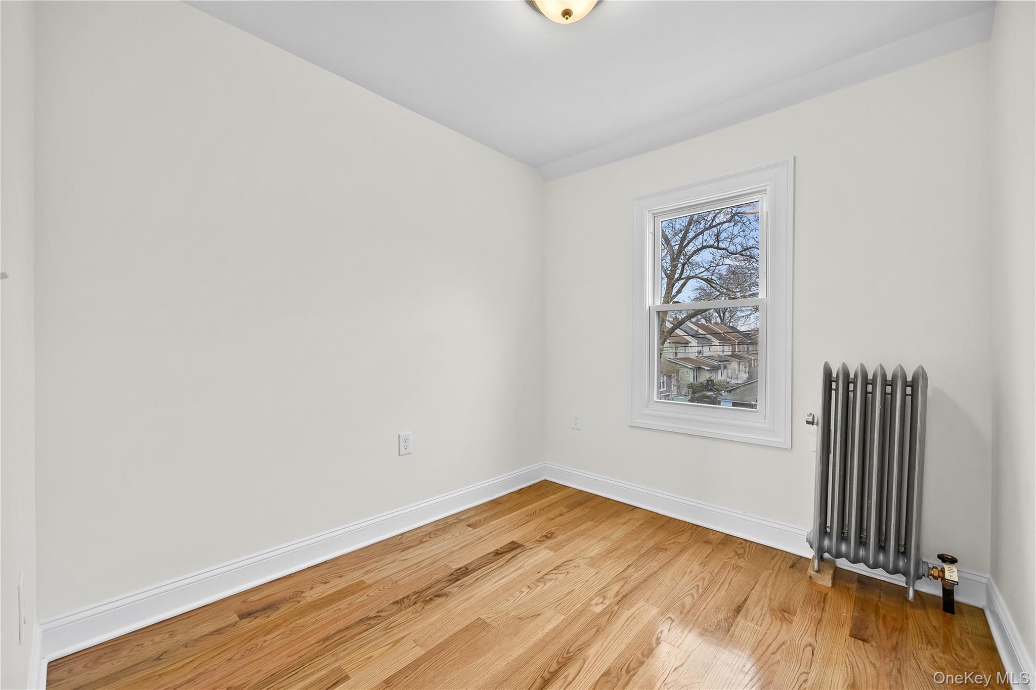 115-12 197th Street Queens, NY 11412 - Photo 17 of 26 an empty room with wooden floor and windows