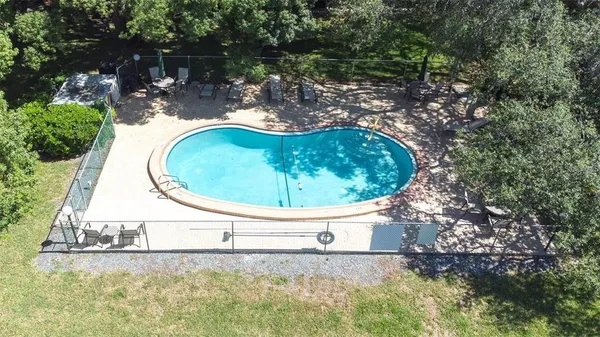 a view of a swimming pool with a yard and large trees