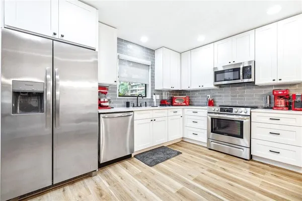 a kitchen with stainless steel appliances cabinets a microwave and a window
