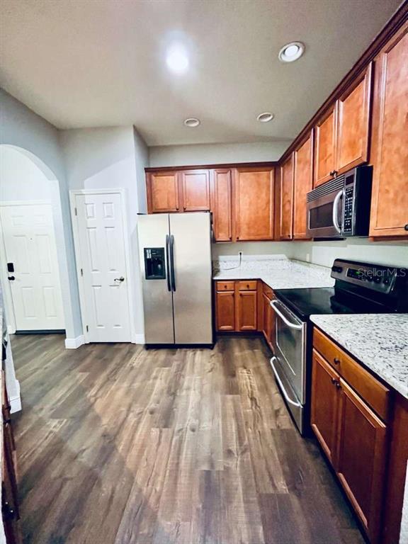 3311 Whitestone Circle, Unit 206 Kissimmee, FL 34741 - Photo 6 of 26 a kitchen with stainless steel appliances granite countertop a refrigerator a sink dishwasher a stove and white countertops with wooden floor