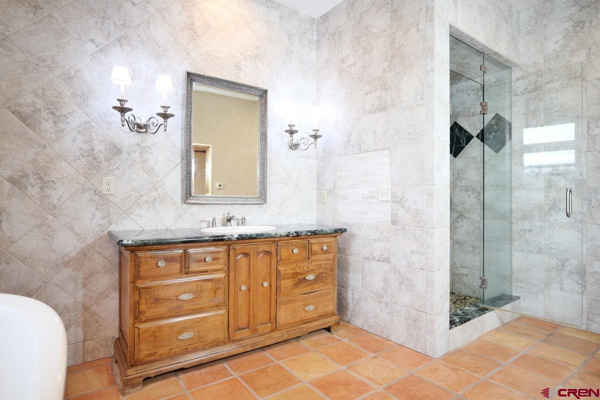 78300 Hunters Ridge Lane Crawford, CO 81415 - Photo 12 of 32 a bathroom with a granite countertop sink a mirror and a shower