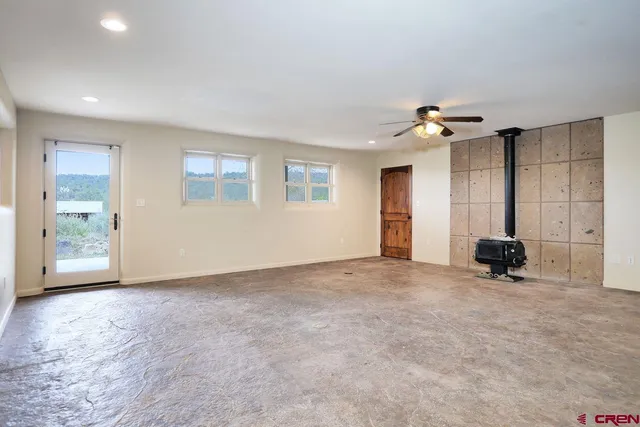 a view of an empty room with wooden floor and windows