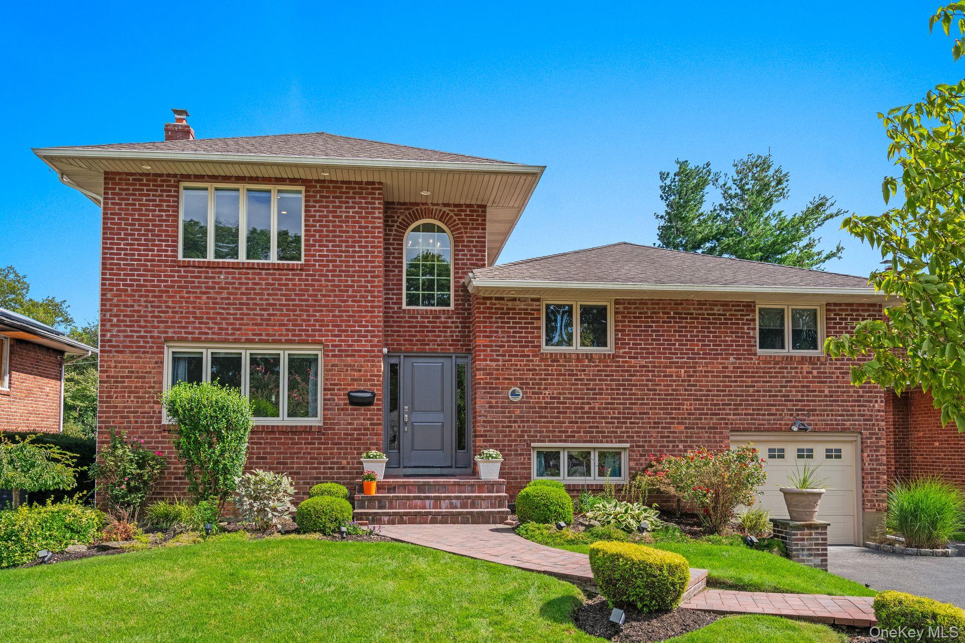 View of front of home with a garage, a chimney, a front lawn, driveway, and brick siding