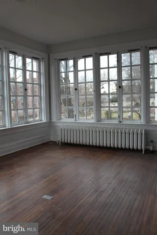 a view of an empty room with wooden floor and windows