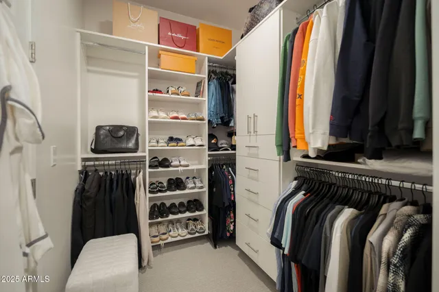 a view of walk in closet with clothes and shoes