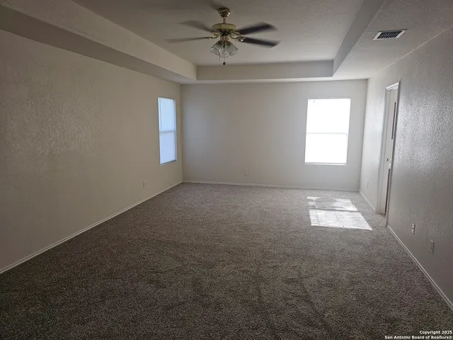 an empty room with windows and fan
