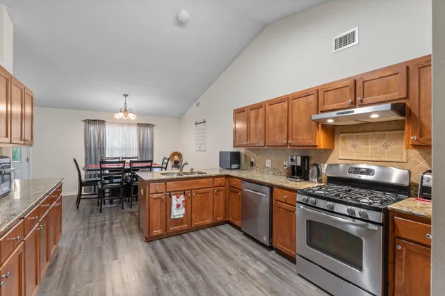 a kitchen with stainless steel appliances a stove a sink dishwasher and cabinets with wooden floor