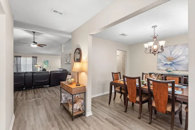 a living room with furniture kitchen view and a wooden floor