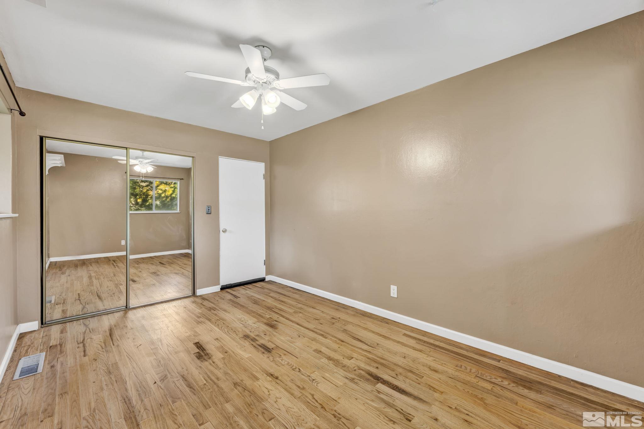 55 Surrey Drive Reno, NV 89521 - Photo 19 of 40 an empty room with wooden floor chandelier fan and windows