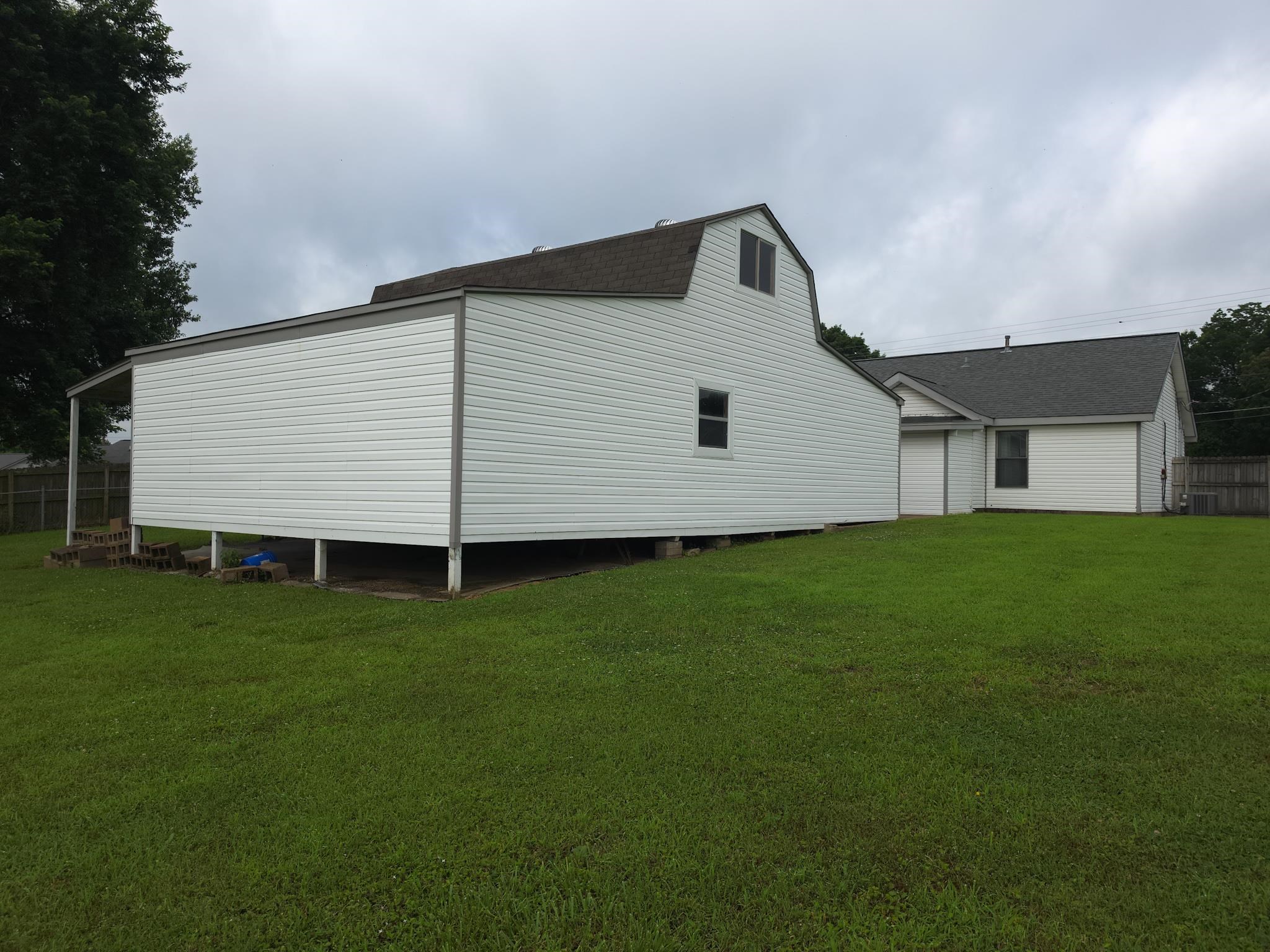 966 Beaver Road Munford, TN 38058 - Photo 27 of 32 Expansive green lawn featuring a white vinyl-sided outbuilding with a gambrel roof and a covered side porch