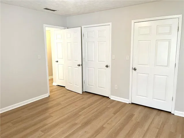 an empty room with wooden floor and closet area