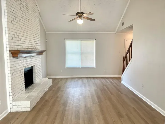 a view of an empty room with wooden floor fireplace and a window