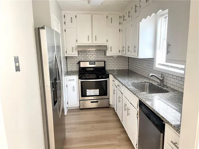 a kitchen with stainless steel appliances granite countertop a sink stove and refrigerator