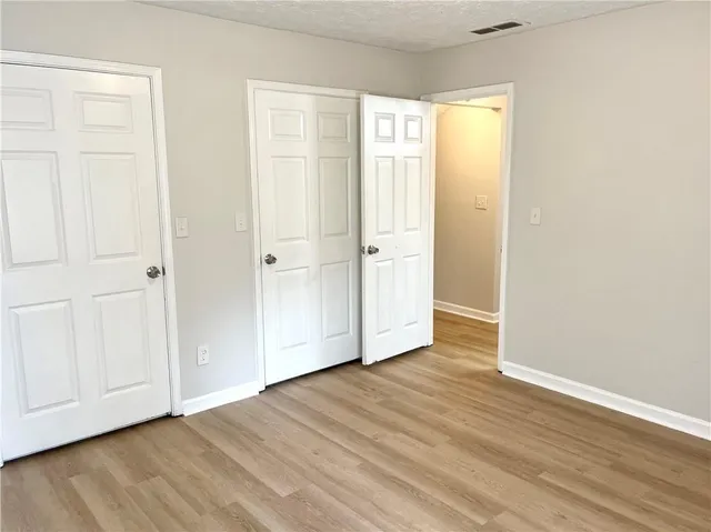 an empty room with wooden floor and closet area