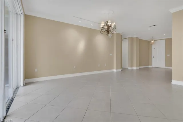 en empty room with a chandelier fan and windows