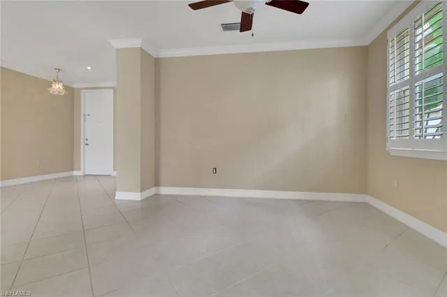 an empty room with windows and chandelier fan