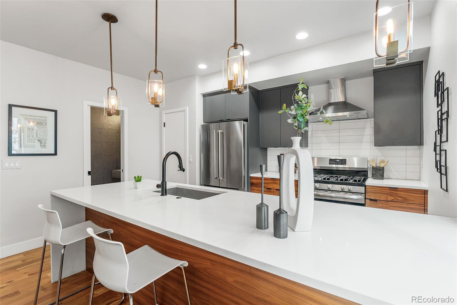 3644 Quivas Street, Unit 2 Denver, CO 80211 - Photo 18 of 49 a kitchen with stainless steel appliances a sink a stove a refrigerator a dining table and chairs with wooden floor