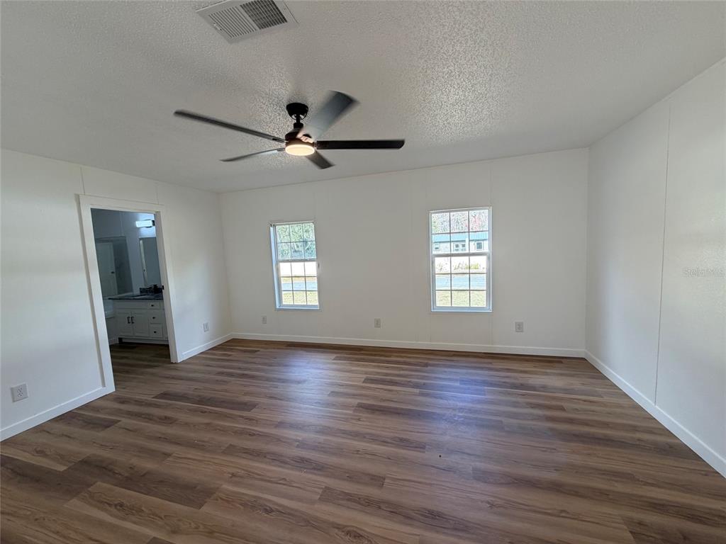 28834 Hubbard Street Leesburg, FL 34748 - Photo 15 of 22 an empty room with wooden floor ceiling fan and windows