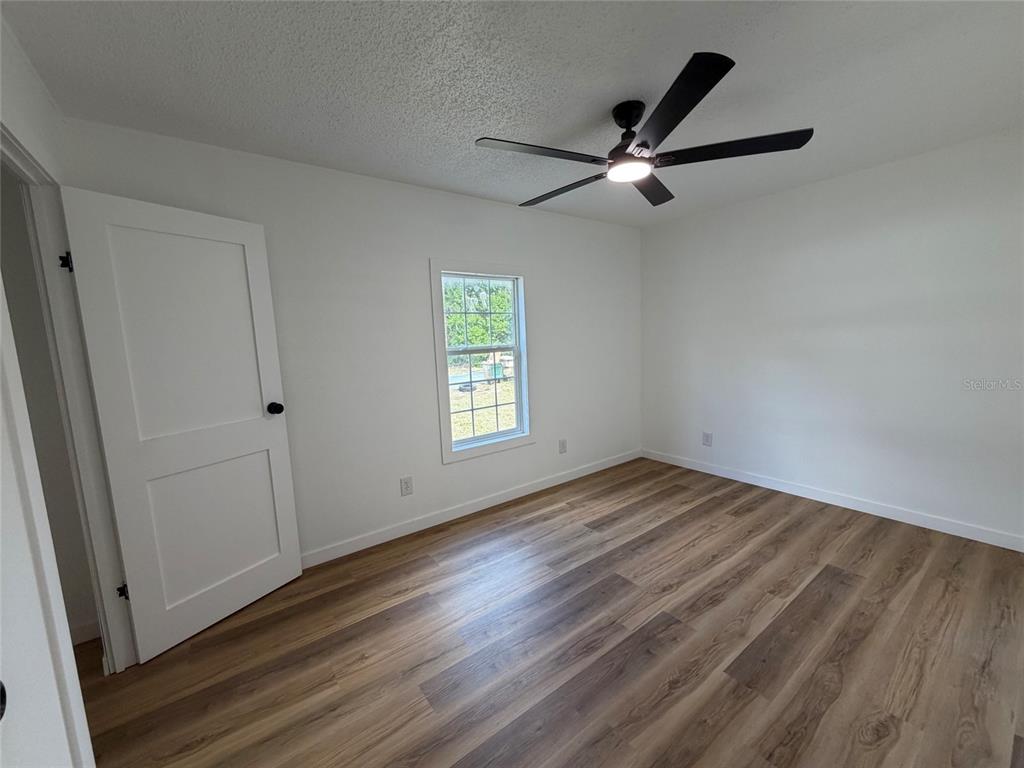 28834 Hubbard Street Leesburg, FL 34748 - Photo 22 of 22 a view of empty room with wooden floor and fan