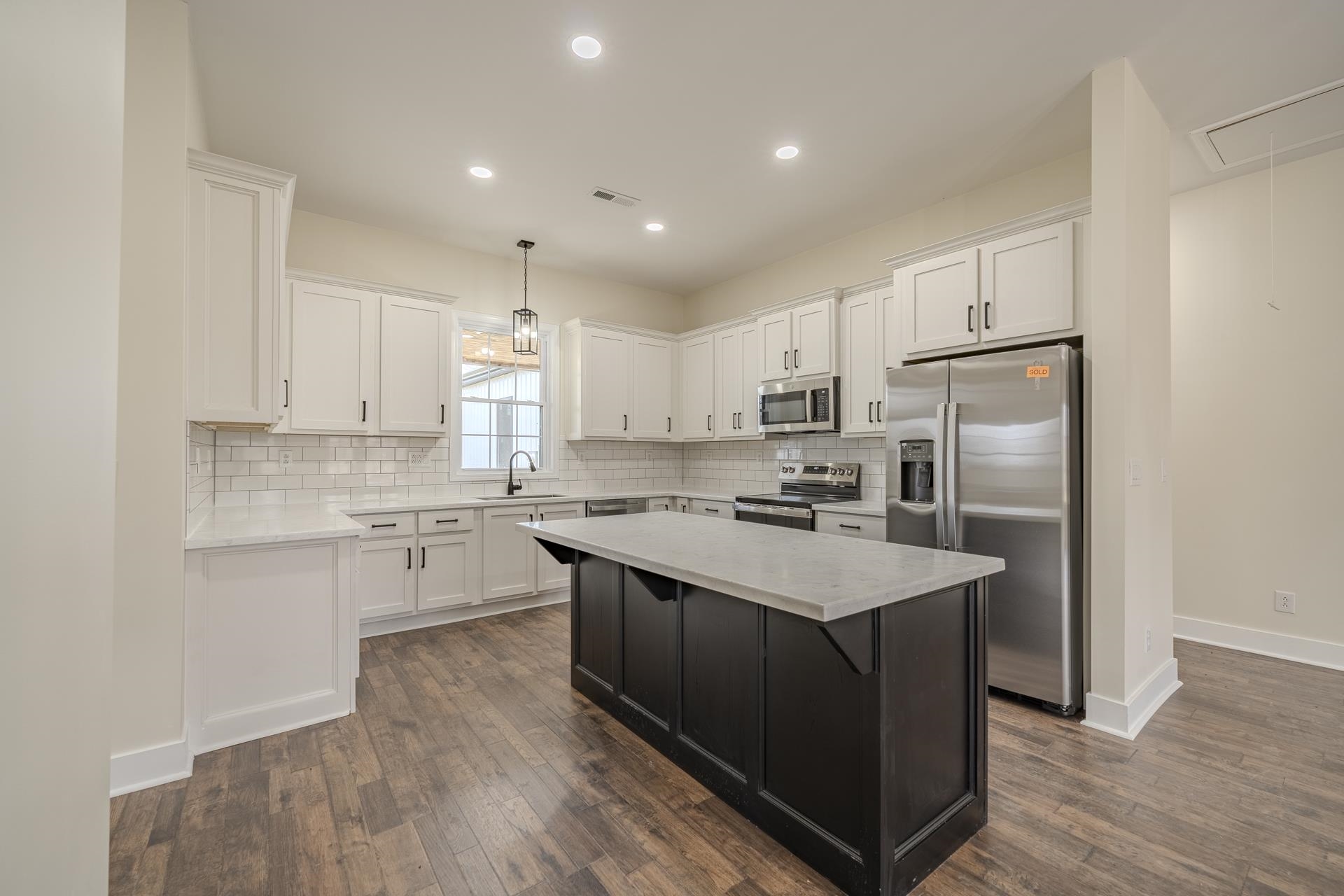 1030 Robbins Road Collinwood, TN 38450 - Photo 11 of 40 Dual tone kitchen with stainless steel appliances, a kitchen island, light stone counters, dark wood finished floors, and two tone cabinets