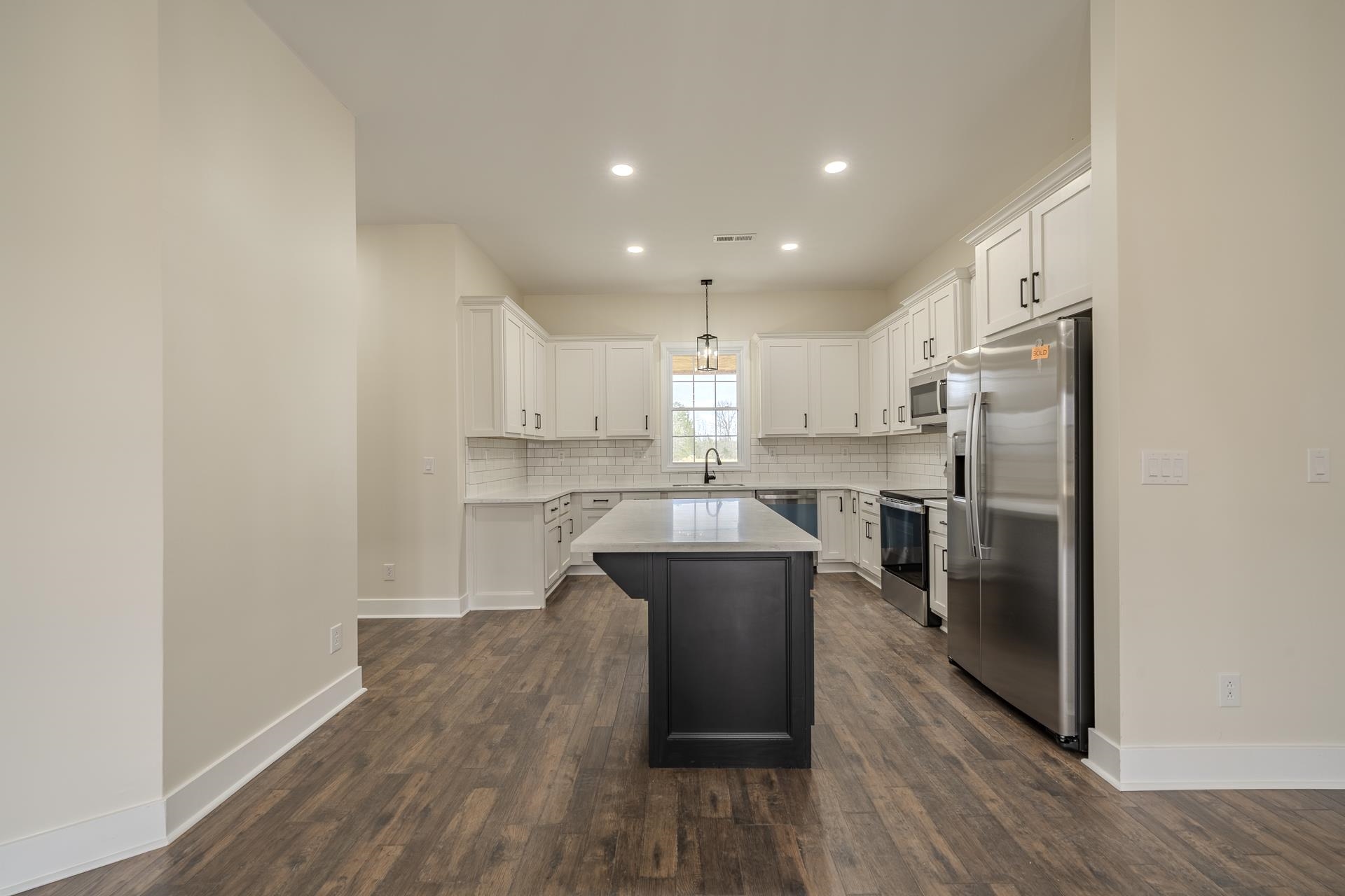 1030 Robbins Road Collinwood, TN 38450 - Photo 12 of 40 Kitchen with stainless steel appliances, a kitchen island, two tone color scheme, decorative backsplash, and hanging light fixtures