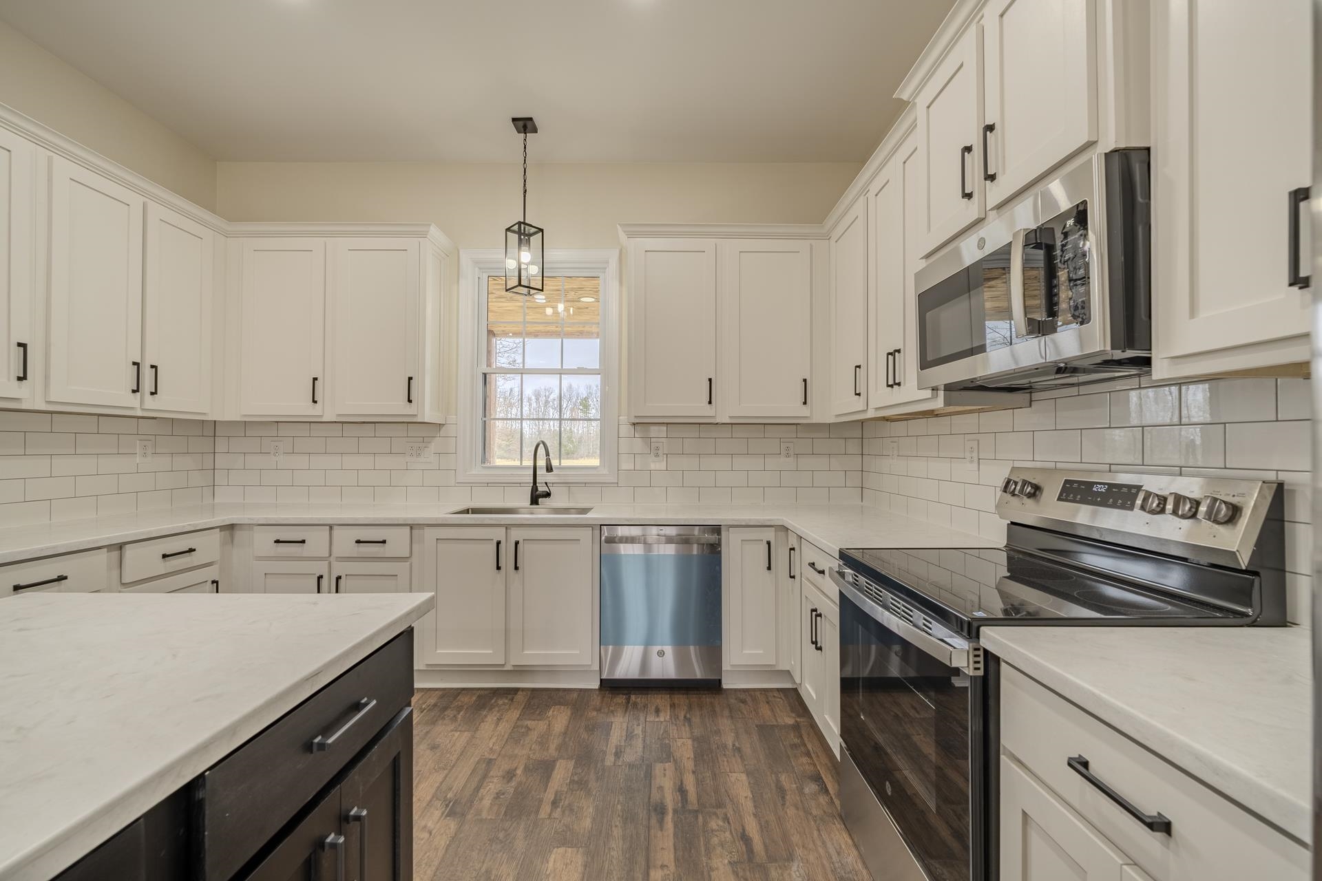 1030 Robbins Road Collinwood, TN 38450 - Photo 13 of 40 Kitchen featuring stainless steel appliances, dark wood finished floors, hanging light fixtures, light stone countertops, and two tone cabinetry