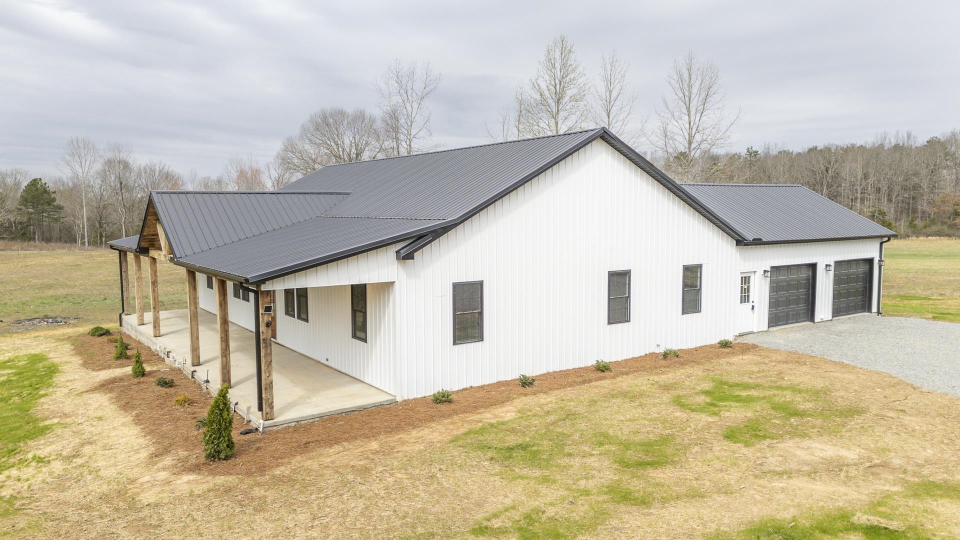 1030 Robbins Road Collinwood, TN 38450 - Photo 31 of 40 View of home's exterior with driveway, a metal roof, a garage, covered porch, and a yard