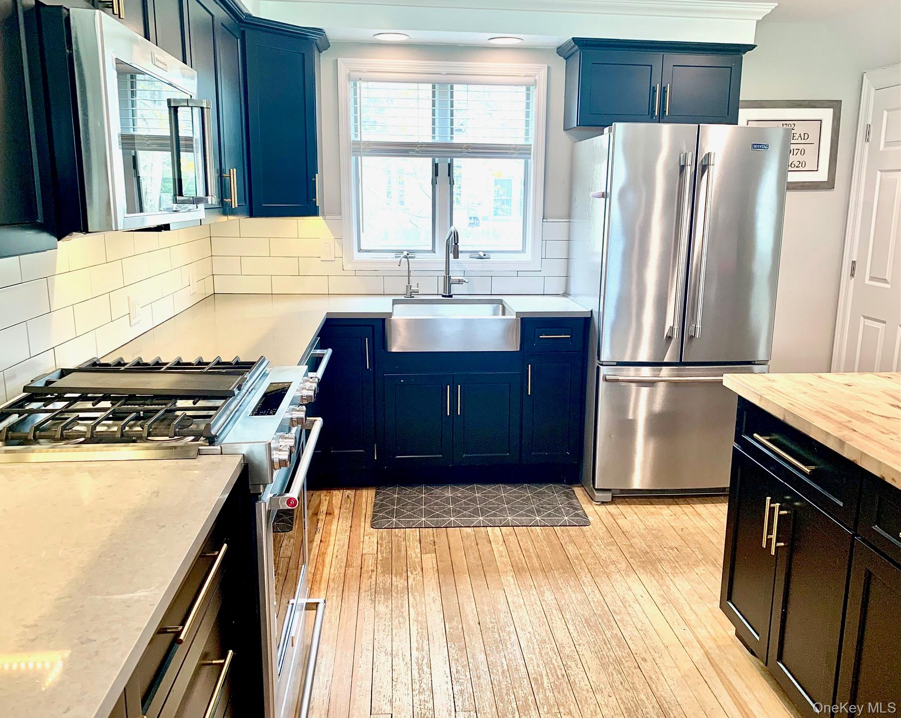 435 Middle Road Riverhead, NY 11901 - Photo 2 of 19 a kitchen with a refrigerator wooden floor and a large window