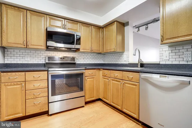 a kitchen with granite countertop white cabinets stainless steel appliances and a sink