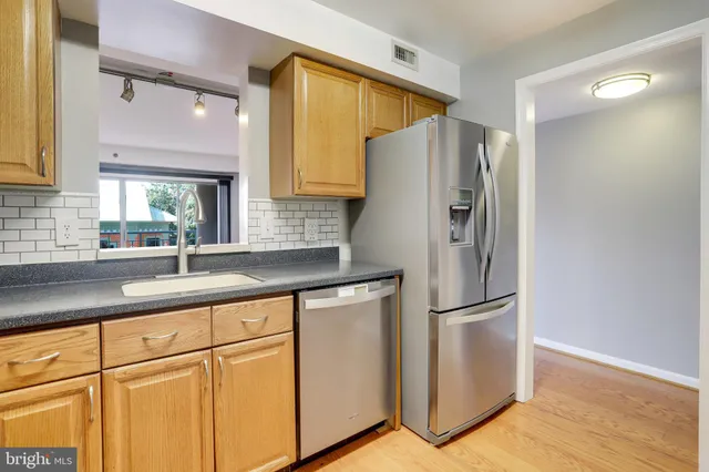 a kitchen with stainless steel appliances granite countertop a refrigerator a sink and white cabinets