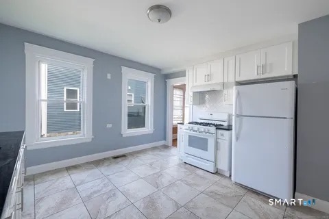 154 Rose Street Bridgeport, CT 06610 - Photo 3 of 6 a kitchen with a refrigerator a stove top oven and cabinets