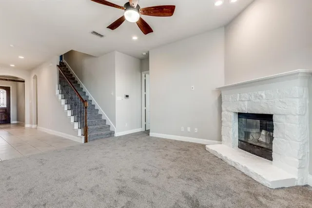 a view of an empty room with chandelier fan and fire place