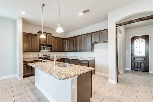 a kitchen with stainless steel appliances granite countertop a sink a stove and a refrigerator