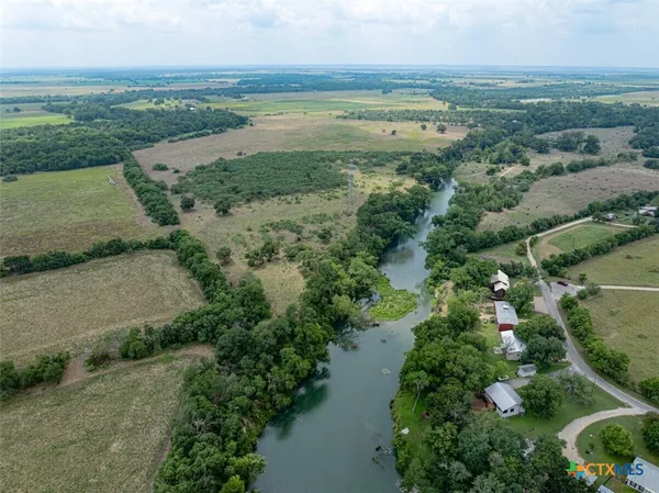 an aerial view of a houses with outdoor space and trees all around