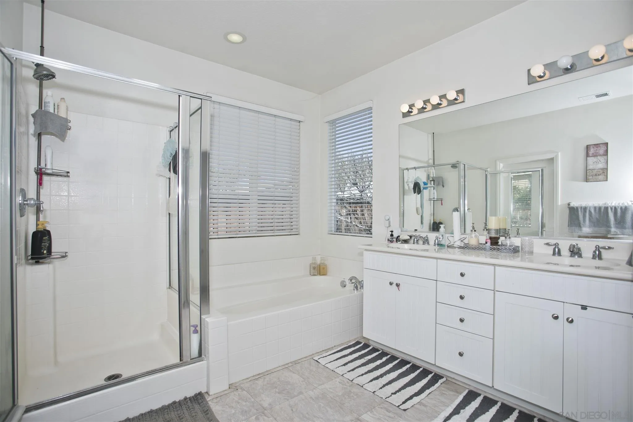 4660 Duskywing Road Hemet, CA 92545 - Photo 16 of 29 a bathroom with a granite countertop sink a mirror a bathtub and shower