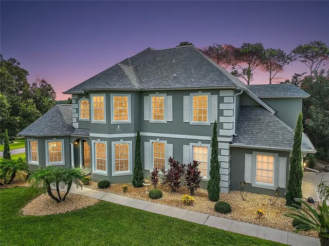 a front view of a house with garden and lots of trees